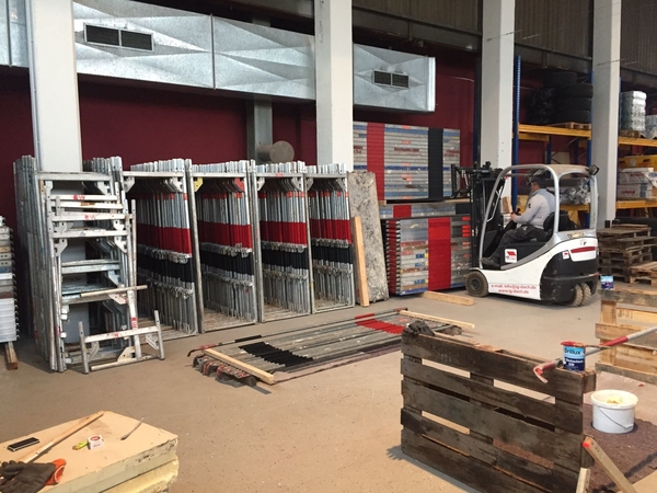Lagerhalle mit Baugerüstteilen, Gabelstapler und Regalen für Gerüstbau und Logistik.