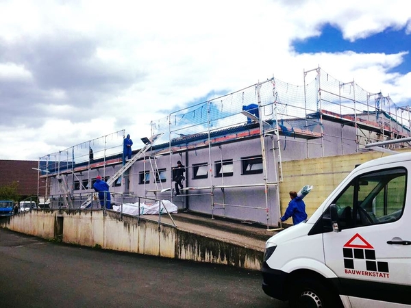 Handwerker führen Fassadenarbeiten an einem eingerüsteten Gebäude mit Bauunternehmen durch.